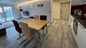 Une cuisine moderne avec un coin repas, un plancher en bois et un téléviseur fixé au mur.
