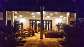 An outdoor dining area with a table and chairs, surrounded by potted plants. - Authentic Beachvilla with cook, private pool, staff and lush tropical garden (Seririt)