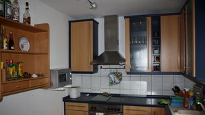 A kitchen with wooden cabinets, a stainless steel range hood, a microwave, and a sink.