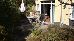 A courtyard with a patio table, a white umbrella, and a stone wall.