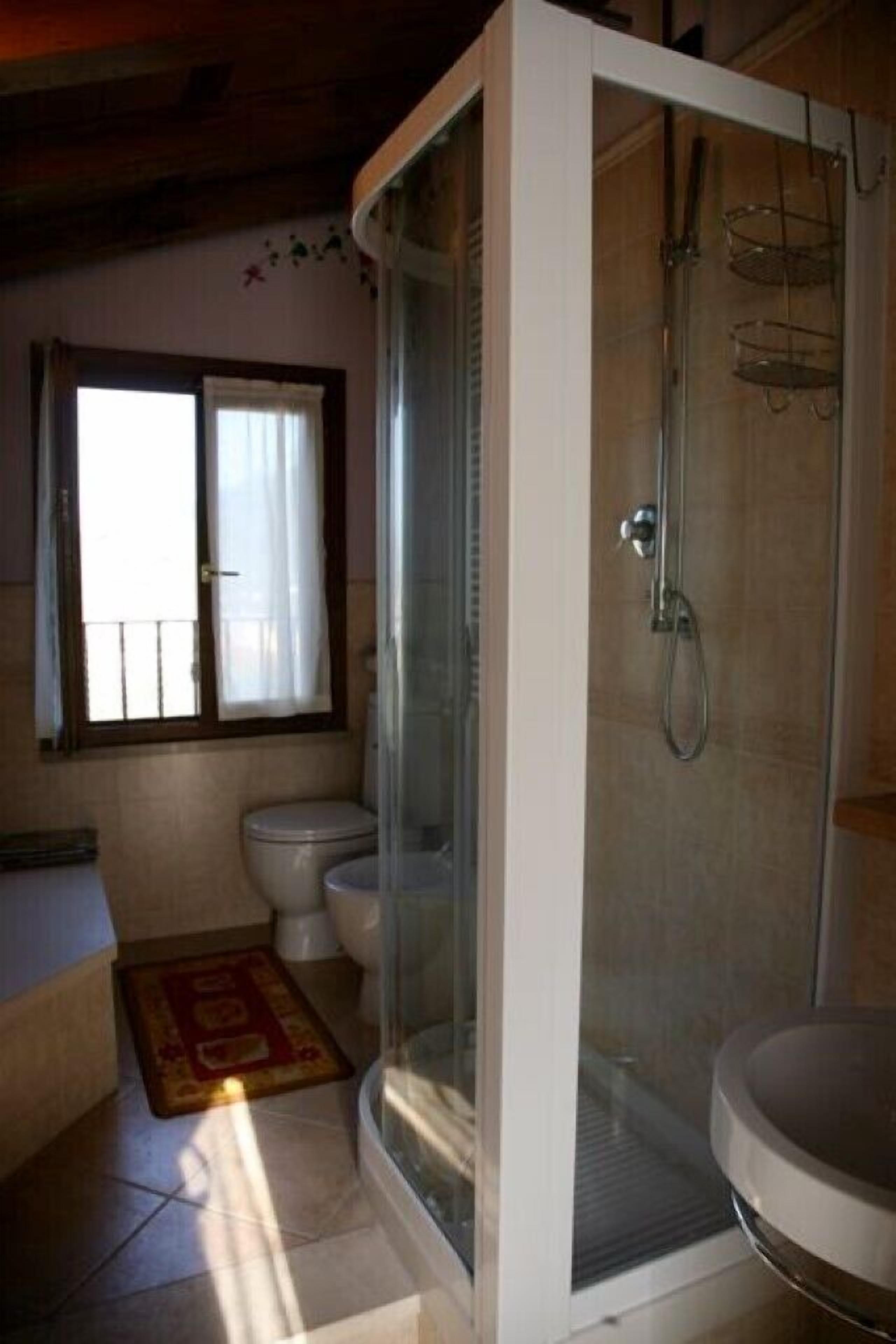 A bathroom with a glass-enclosed shower, a toilet, and a sink.