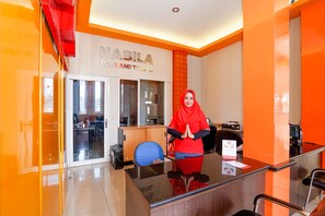 Una reception con una donna dietro, un ingresso con porta in vetro e un cartello con scritto 'NABILA TOUR AND TRAVEL'.