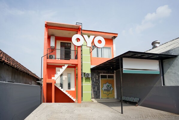 Un edificio di due piani con un cartello ben visibile con la scritta "OYO", una scala e una porta con un logo.