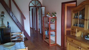 A staircase leading to a second floor, a wooden cabinet with glass doors, and a shelf with books and decorative items.