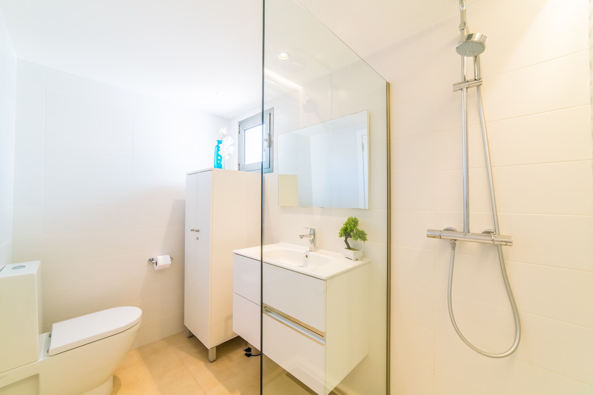 A modern bathroom with a toilet, a sink, a mirror, and a shower.