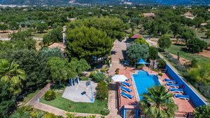 Oversigtsbillede af et resort med swimmingpool, liggestole og et bjerglandskab i baggrunden.