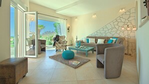 Un salon spacieux doté d’une grande fenêtre, d’un mur décoratif en pierre et d’un coin salon confortable avec un canapé et des fauteuils.