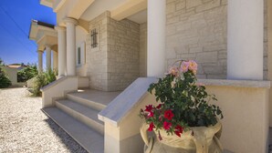 Un bâtiment à la façade en pierre, un escalier menant à une porte et un pot de fleurs contenant des fleurs roses et rouges.