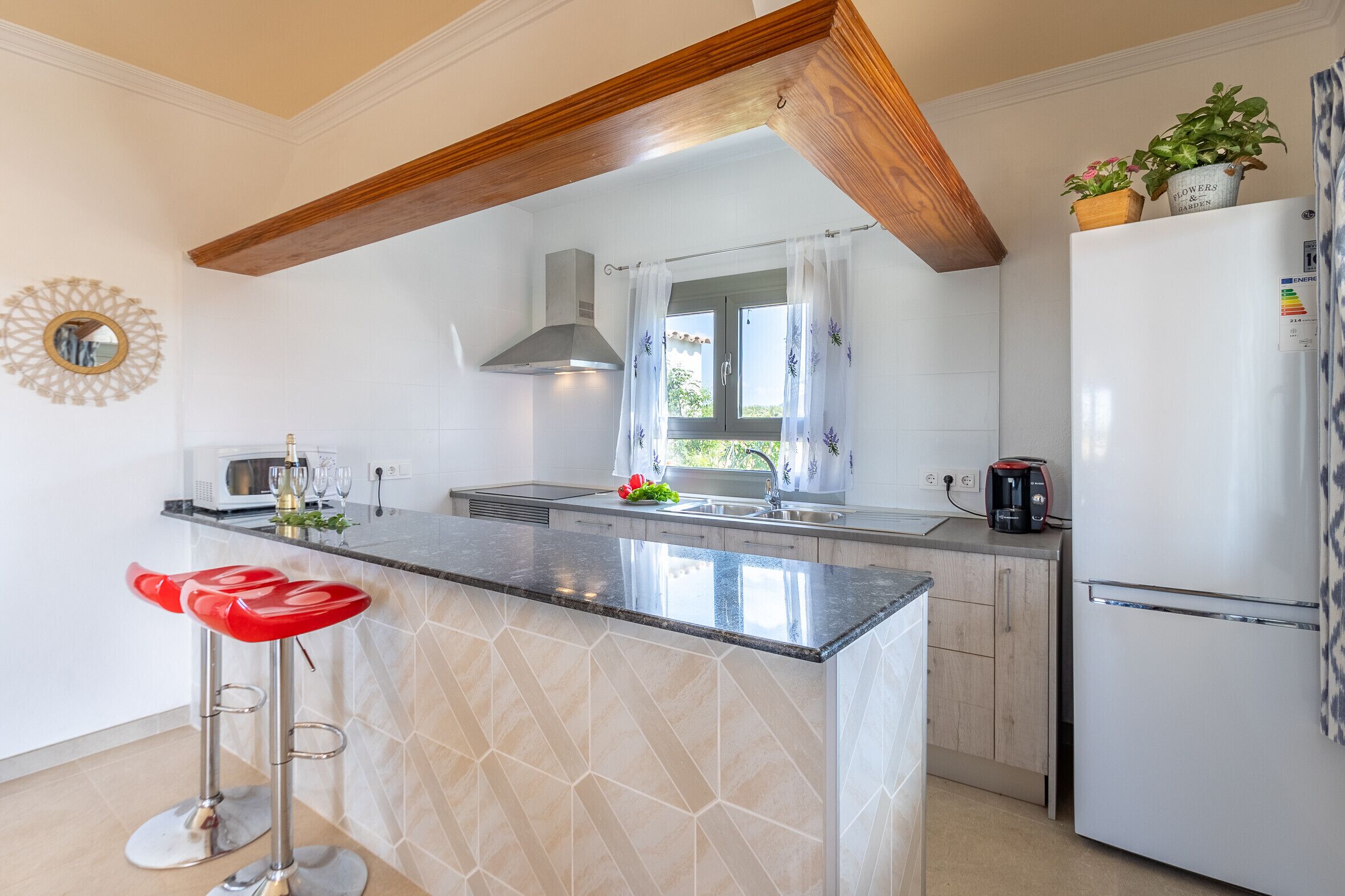 A modern kitchen with a central island, a built-in oven, and a refrigerator.