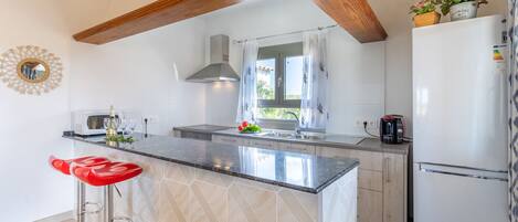 A modern kitchen with a central island, a built-in oven, and a refrigerator.