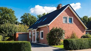 A two-story brick house with a sloped roof, a garage, and a well-maintained front yard with hedges. - Feha - Holiday House "Minnet", 15169 (Leer (Ostfriesland))