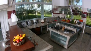Cozinha moderna com uma ilha grande, banquetas e vista para um campo de golfe.