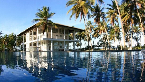 Um hotel com piscina, rodeado por palmeiras.