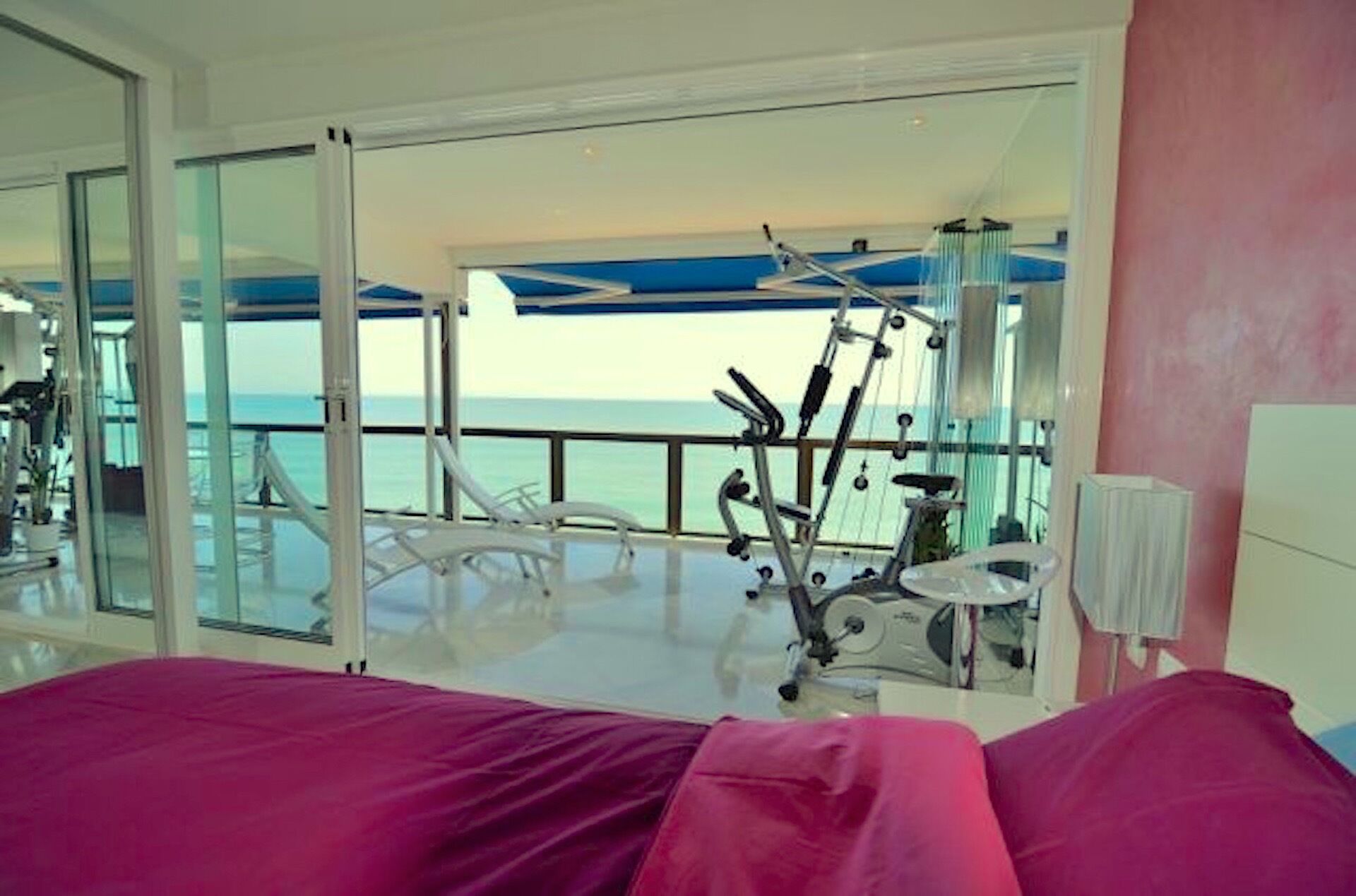 Une chambre avec un lit, du matériel d’exercice et une vue sur la mer.