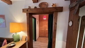 Un couloir en bois avec une porte verte, un chambranle de porte en bois et une lampe posée sur une table en bois.