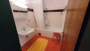 Bañera con ducha, toallas, jabón, shampoo