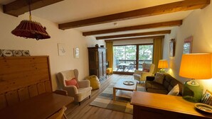 Un salon chaleureux avec des poutres en bois, une table à manger, un canapé et une table basse.