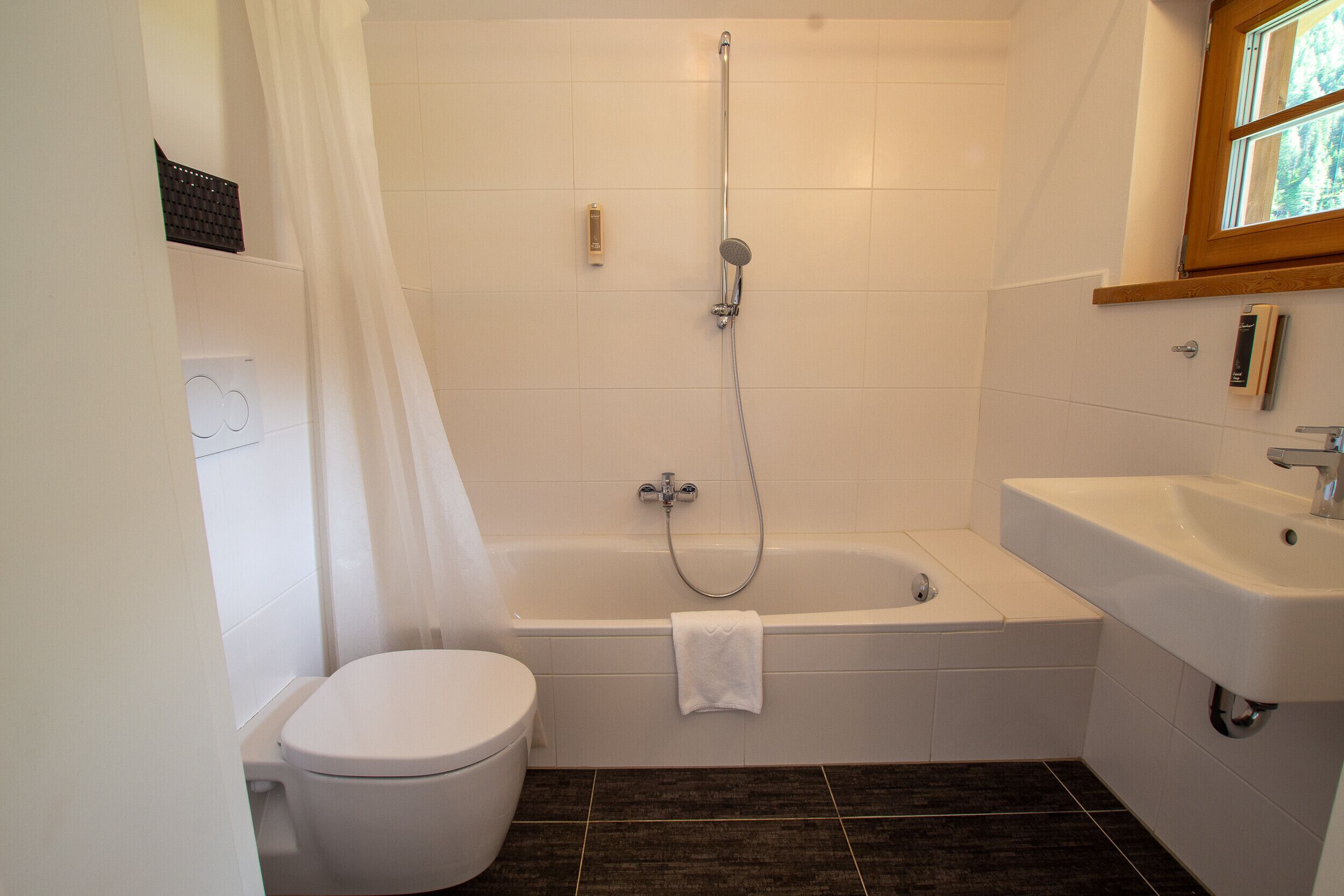 Une salle de bain comprenant des toilettes, une baignoire avec pomme de douche et un lavabo.