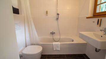 Une salle de bain comprenant des toilettes, une baignoire avec pomme de douche et un lavabo.