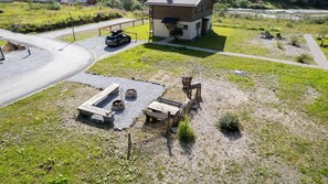 Un chalet rustique doté d’une terrasse en gravier, de bancs en bois et d’un foyer.