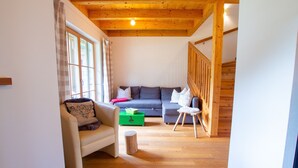 Un salón acogedor con un sofá, una silla, una mesita y un caja de almacenamiento verde.