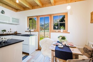 A modern kitchen with white cabinets, a black countertop, and a large window offering a mountain view. - Lodge Adlerhorst 178 im Tauerndorf Enzingerboden (Uttendorf)