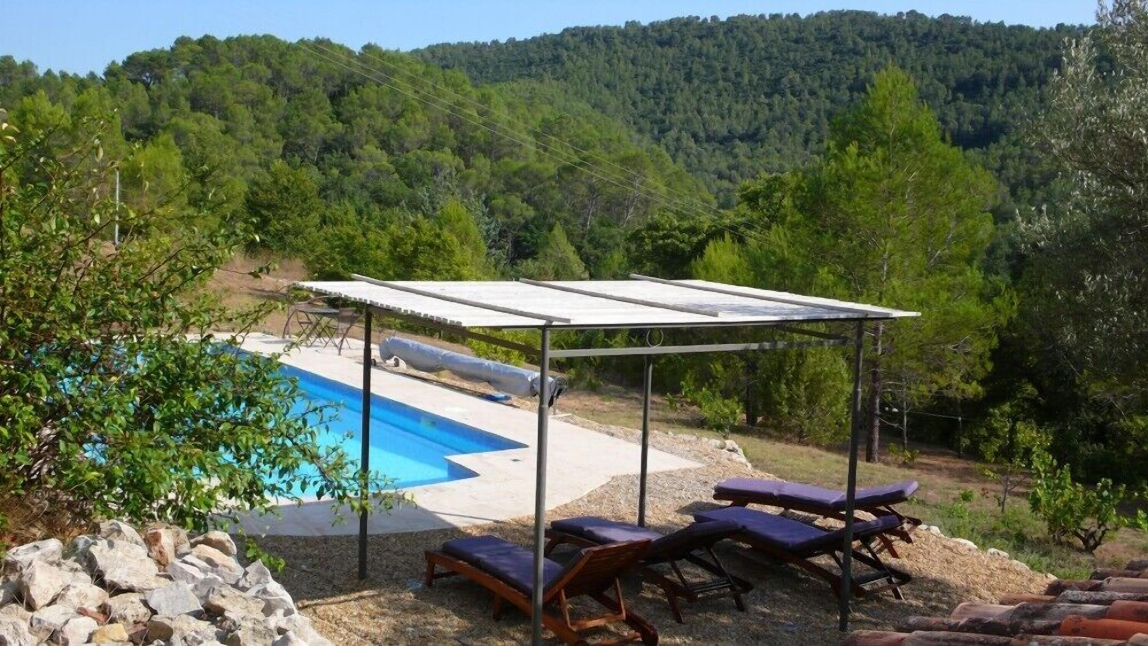 A pool area with a covered seating area and lounge chairs.