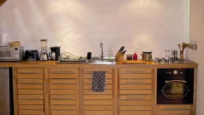 A kitchen with wooden cabinets, a microwave, a coffee maker, a blender, and an oven. - Maisonette apartment in historic Quito, with fantastic garden (Quito)