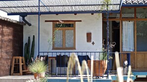 A traditional building with a tiled roof, a wooden door, and a balcony with chairs and potted plants. - Maisonette apartment in historic Quito, with fantastic garden (Quito)