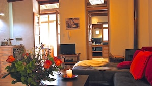 A cozy living room with a sofa, a coffee table with a candle, and a vase of flowers. - Maisonette apartment in historic Quito, with fantastic garden (Quito)