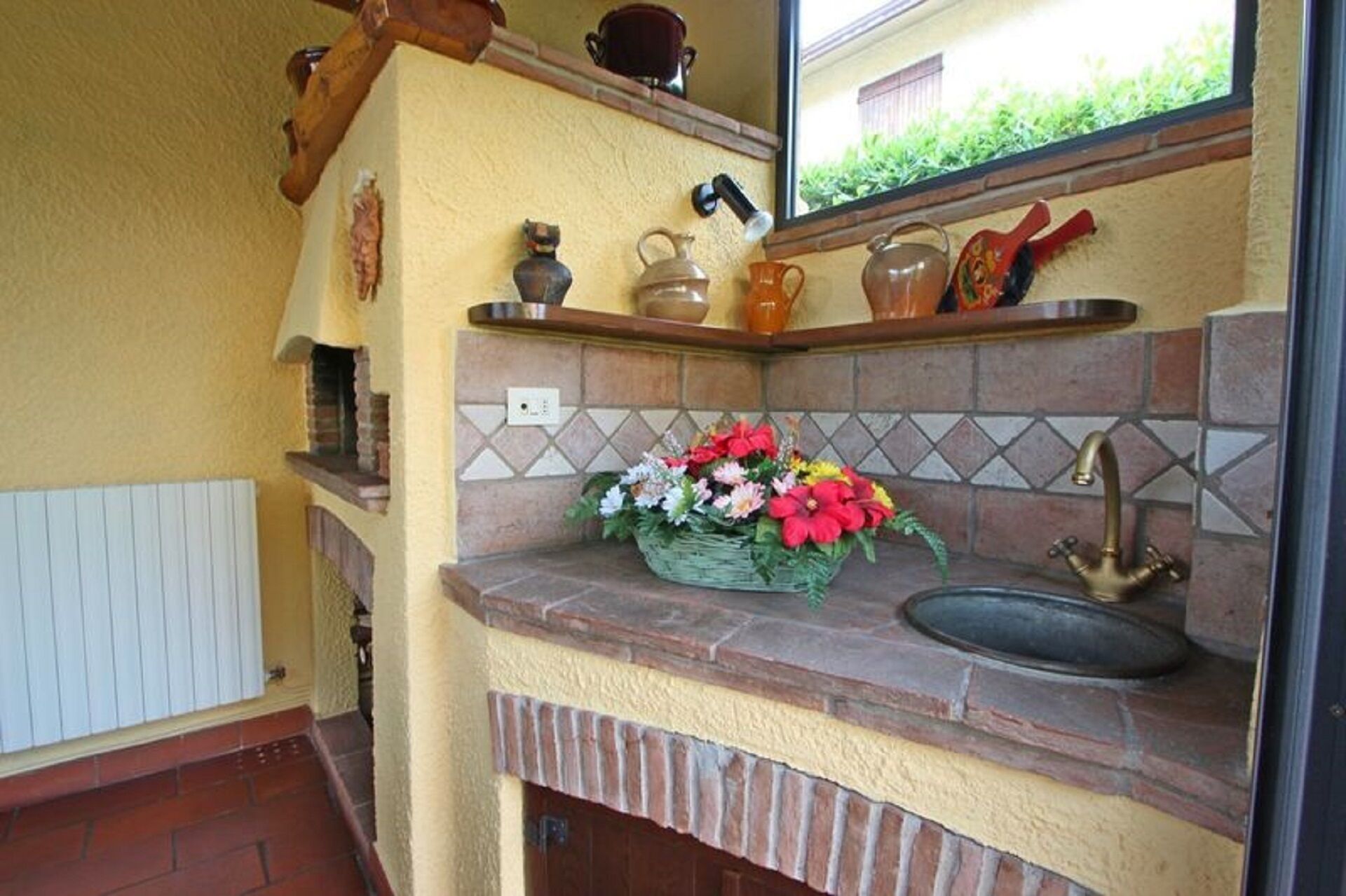 A kitchen with a stone countertop, a sink, and a backsplash with a diamond pattern. There is a basket of flowers on the countertop.
