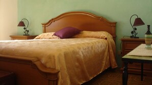 A bedroom with a wooden bed, a single purple pillow, and two bedside lamps.