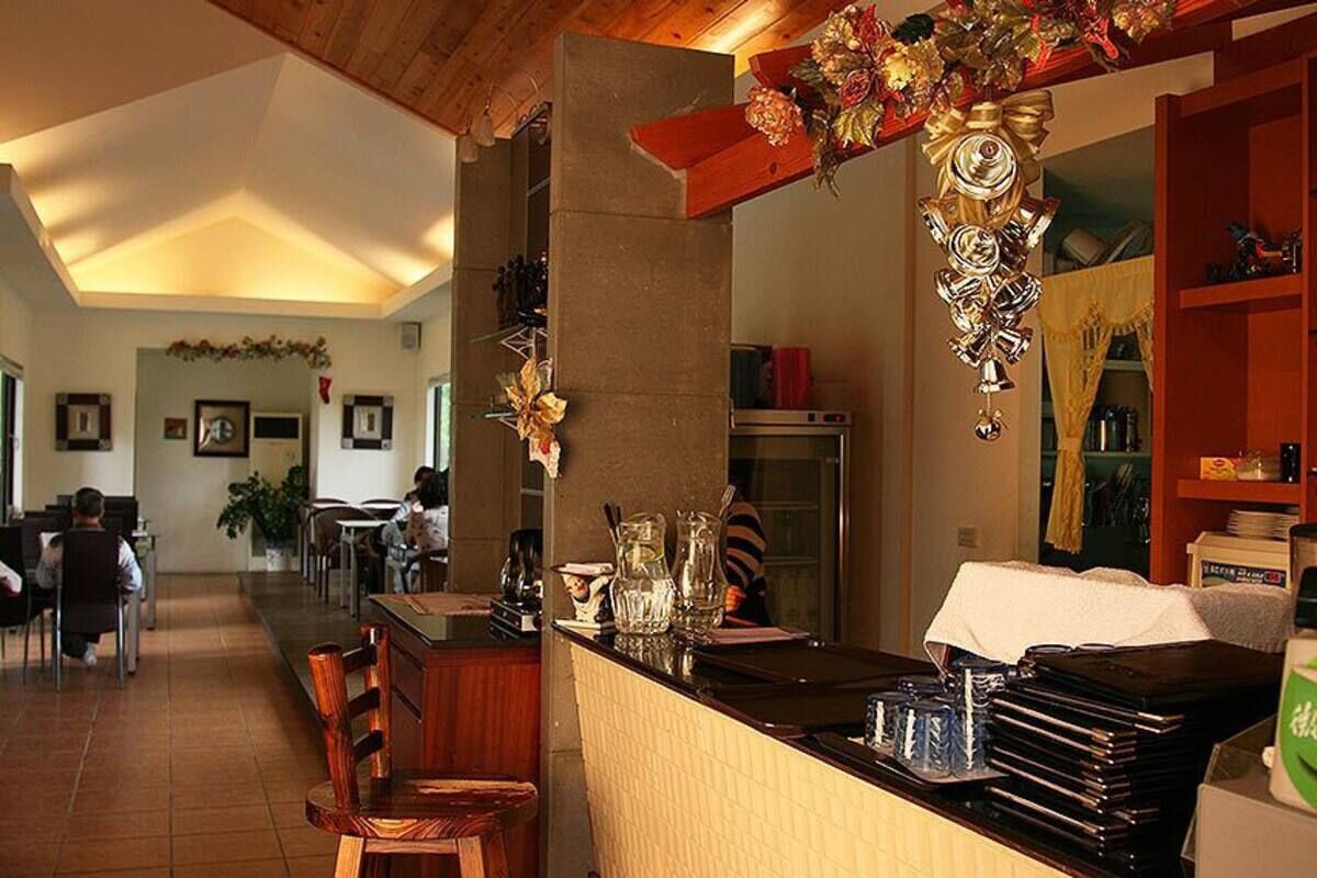 A restaurant with a bar area, wooden chairs, and a tiled floor.