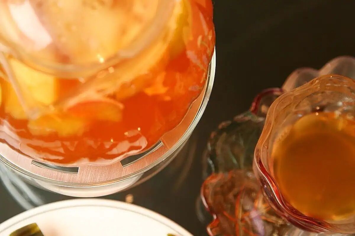 Un vaso con líquido rojo, posiblemente una bebida, y un vaso transparente con líquido dorado.