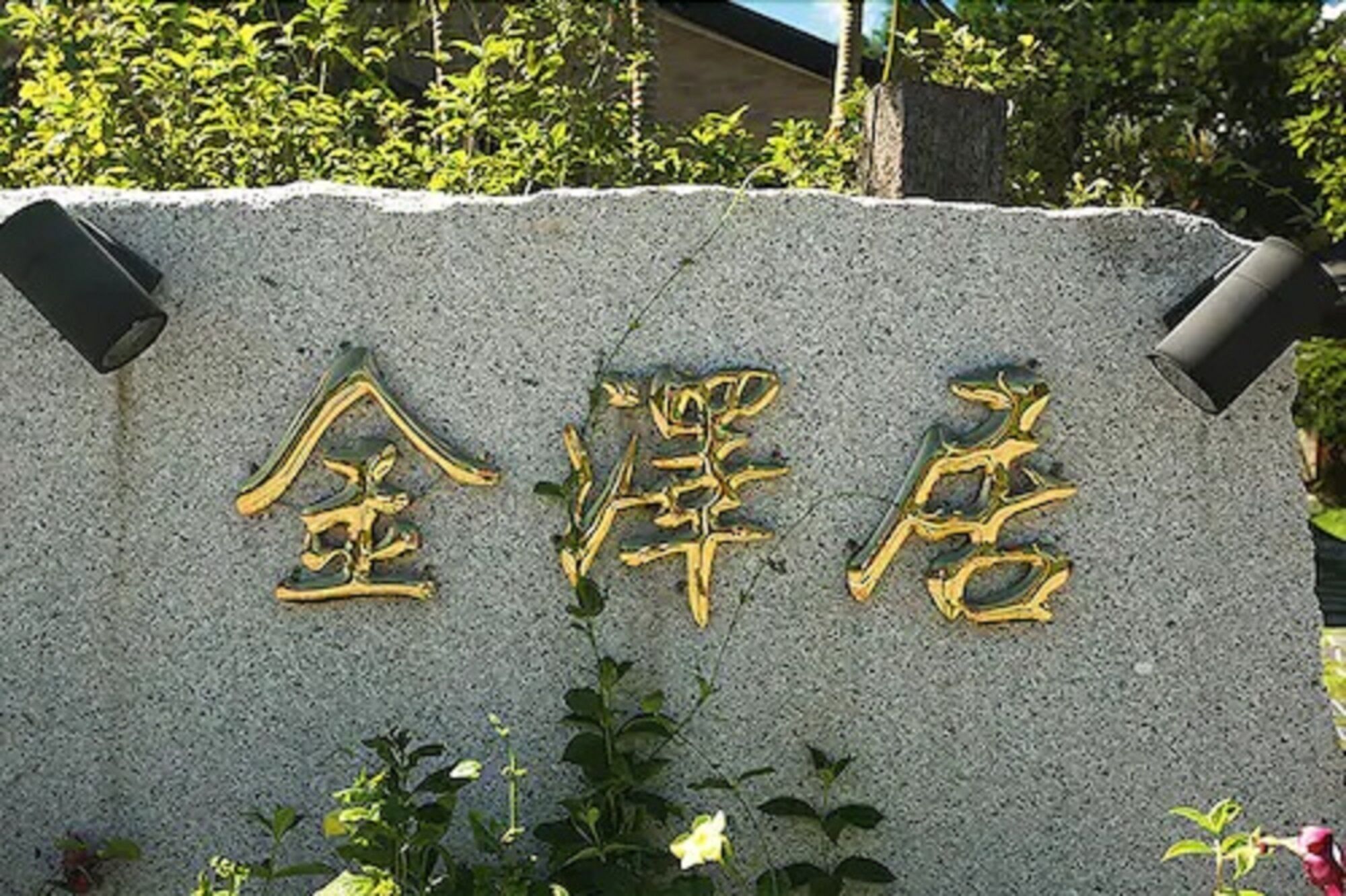 Un letrero de piedra con letras doradas, probablemente indicando un hotel u otro establecimiento.
