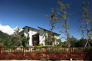 A modern two-story house with a white exterior and dark roof, surrounded by lush greenery and a red fence. - Kanazawa House (Ji'an)