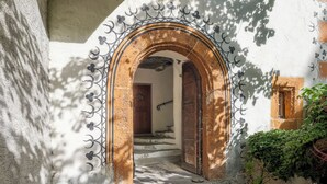 An arched doorway leading to a staircase, surrounded by a white wall with decorative metalwork.