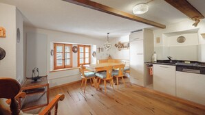 A cozy kitchen with wooden flooring, a dining table with chairs, and a built-in oven.