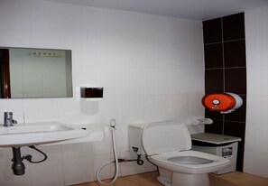 Un baño con lavamanos, inodoro y secamanos.