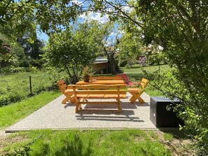 A wooden picnic table with benches in a garden setting. - Detached vacation home in a quiet cul-de-sac - dogs welcome - WiFi included (Bad Sachsa)