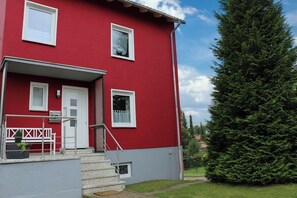 A red building with white trim, a front door, and a small porch with steps. - Detached vacation home in a quiet cul-de-sac - dogs welcome - WiFi included (Bad Sachsa)