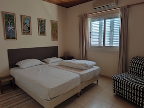 Habitación de hotel con dos camas, una silla, una mesita de noche y decoración en la pared.