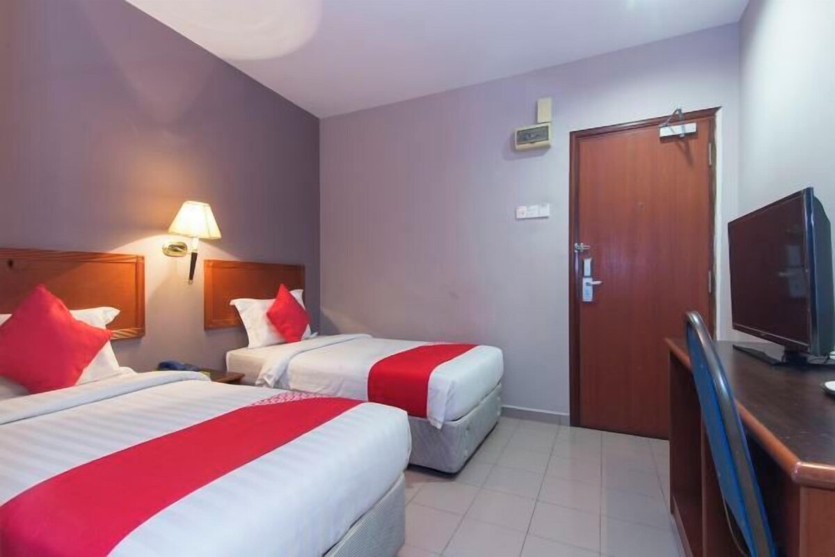 Habitación de hotel con dos camas, televisión, escritorio y puerta.