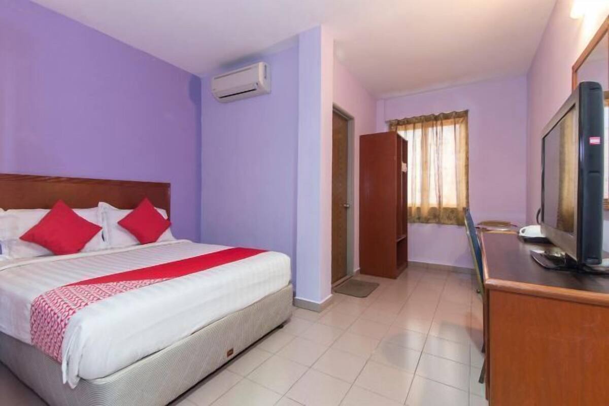 A hotel room with a bed, a television, and a wooden desk.