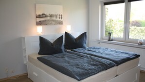 Un dormitorio con cama, lámparas de noche, una ventana con vistas y una obra de arte colgada en la pared.