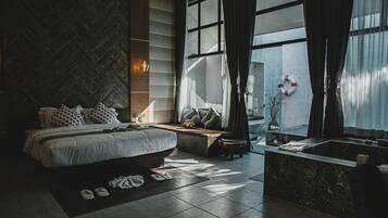 Ein modernes Schlafzimmer mit einem großen Bett, einer eingebauten Bank, einer Badewanne und Blick ins Freie.