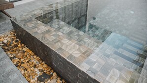 A modern outdoor pool area with a glass enclosure and a pebble-lined border. - Arun Dara Villa (Chiang Mai)