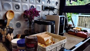 A kitchen counter with a toaster, a coffee maker, a jar of peanut butter, a bottle of chocolate topping, and a basket of bread. - Arun Dara Villa (Chiang Mai)