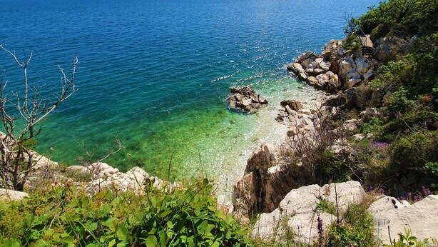 Un paysage côtier caractérisé par des eaux limpides, une côte rocheuse et une végétation luxuriante.