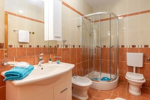 Ein Badezimmer mit Duschkabine, Waschbecken, Bidet und Toilette.